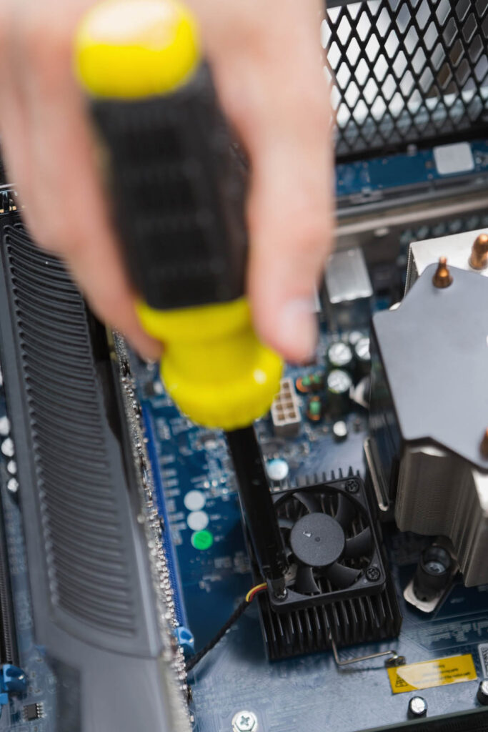 Hand using screw drive to fix processor fan