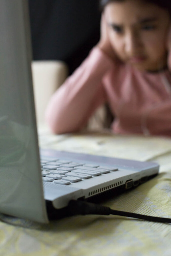 Young girl thinking over a problem at the table with laptop at h